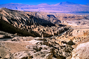 Eroded desert landscape with a road winding through mountains.