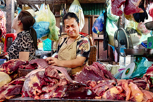 Market vendor with fresh meat display. by Marco Brivio