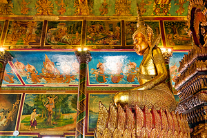 Golden Buddha statue and intricate murals in a temple. by Marco Brivio