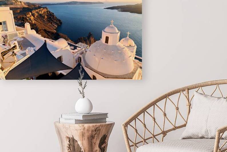 White churches overlook Santorini caldera and sea at sunset. by Marco Brivio