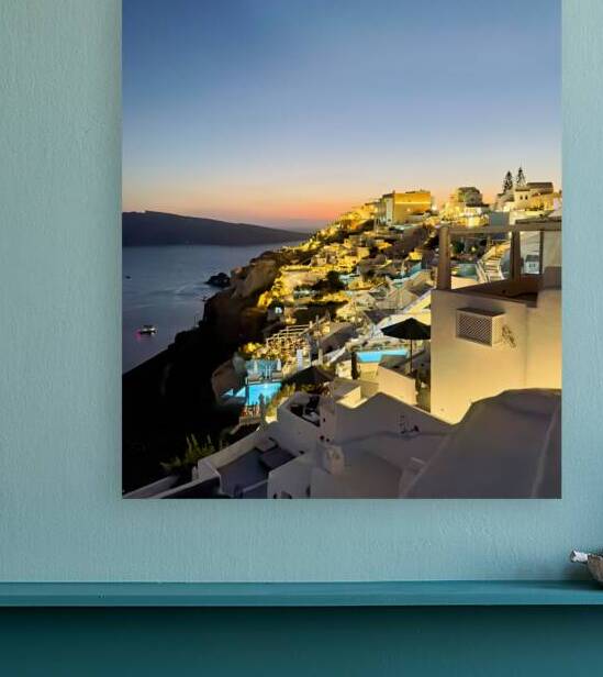 Illuminated cliffside village at sunset over the ocean. by Marco Brivio