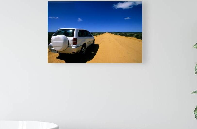 A white SUV on a long straight outback road. by Marco Brivio