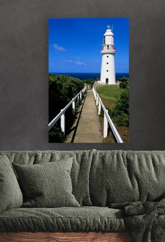 A white lighthouse overlooks the ocean on a sunny day. by Marco Brivio