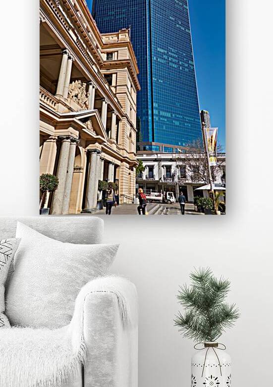 Modern skyscraper dwarfs historic building under clear blue sky. by Marco Brivio