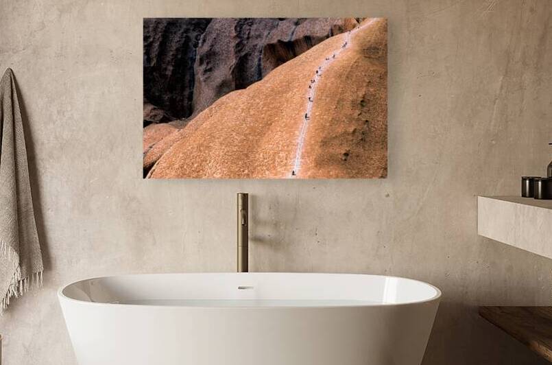 Hikers ascend Uluru using a chain ladder in Australia. by Marco Brivio