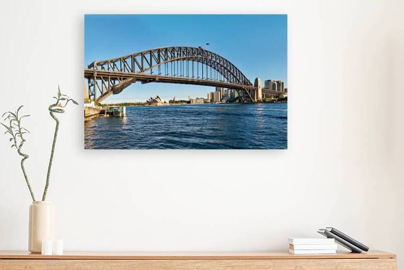 Sydney Harbour Bridge and Opera House under clear blue sky. by Marco Brivio