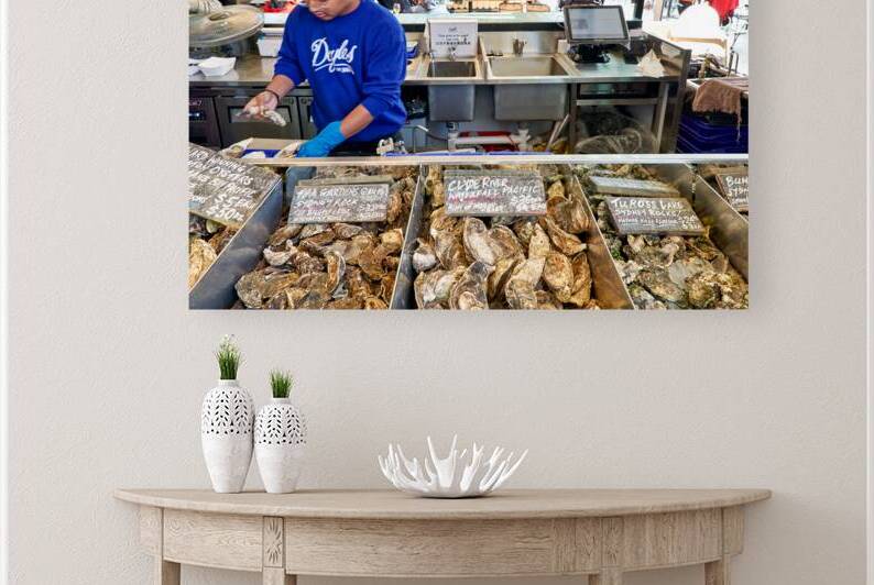 Oyster vendor prepares fresh oysters for customers at market. by Marco Brivio