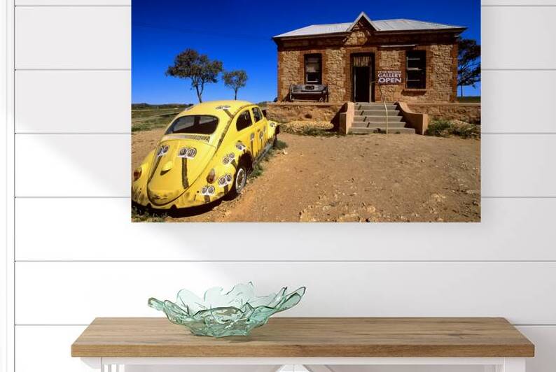 A painted yellow Beetle outside a rural stone gallery. by Marco Brivio
