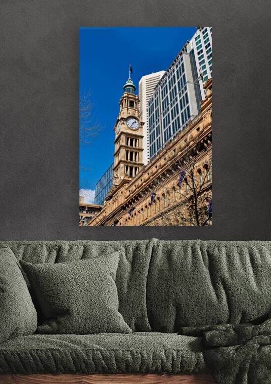 Historic clock tower stands tall against modern buildings. by Marco Brivio