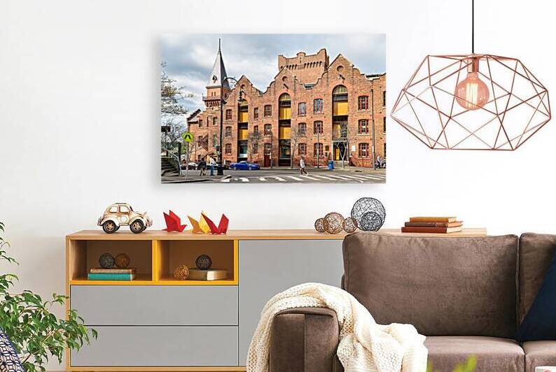 Historic brick building with a tower and people walking. by Marco Brivio