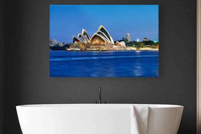 Sydney Opera House illuminated at dusk over the harbor. by Marco Brivio