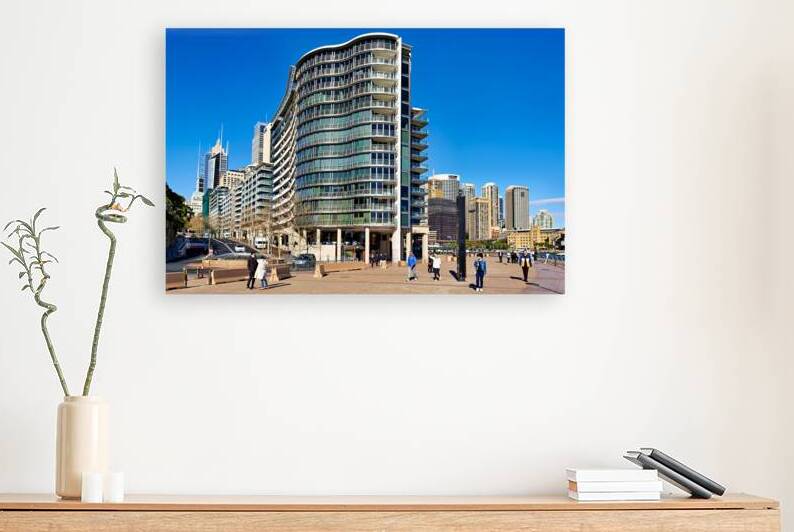 Modern curved building with balconies and city skyline. by Marco Brivio
