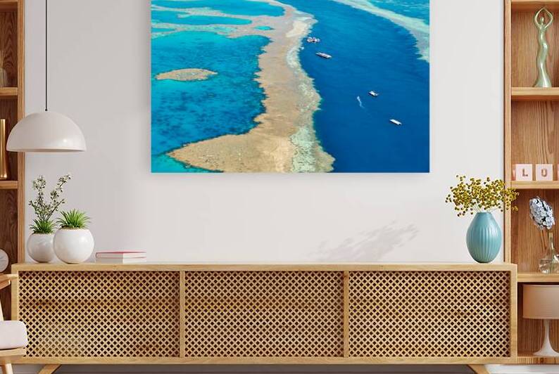 Aerial view of coral reefs and boats in turquoise ocean. by Marco Brivio