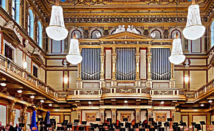 Ornate concert hall with organ chandeliers and empty orchestra by Marco Brivio