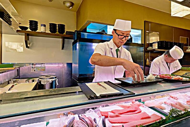 Preparing sushi in a sushi bar in Shibuya Tokyo Japan during t by Marco Brivio