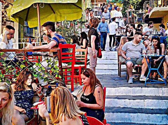 Dining and socializing in a crowded outdoor cafe in a city by Marco Brivio