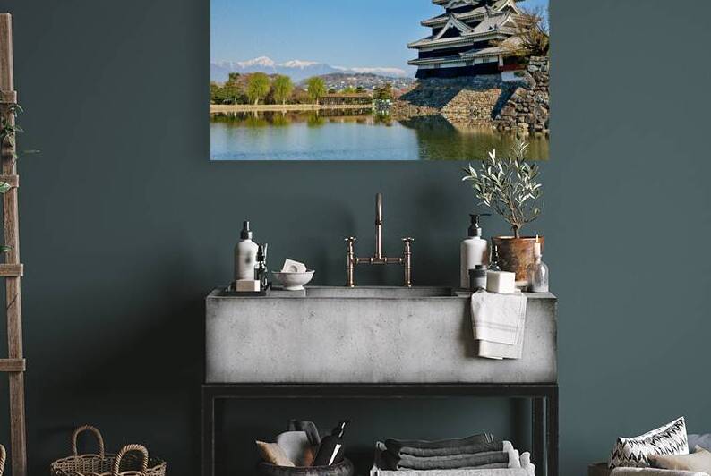 Matsumoto Castle stands beside water with mountains in the dista by Marco Brivio