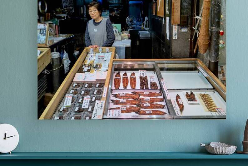 Fishmonger stands by fresh seafood displays in Nishiki Market K by Marco Brivio