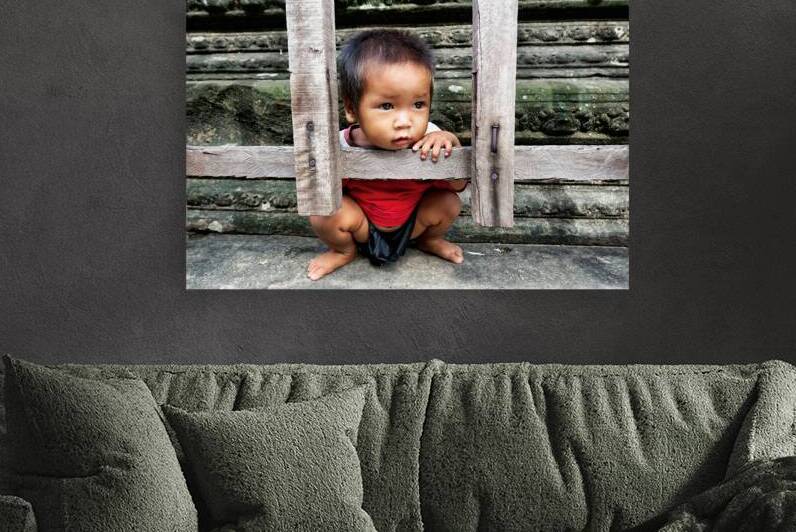 Curious child peeking through wooden frame at ancient ruins. by Marco Brivio