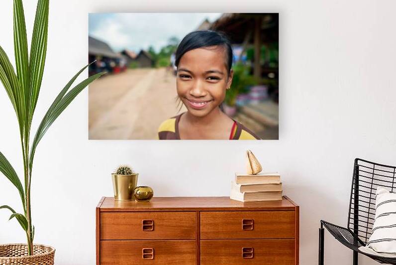 Smiling young girl in a village setting. by Marco Brivio