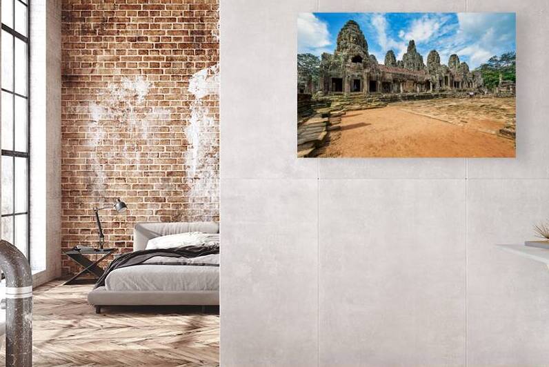 Ancient Bayon temple with stone faces under a blue sky. by Marco Brivio