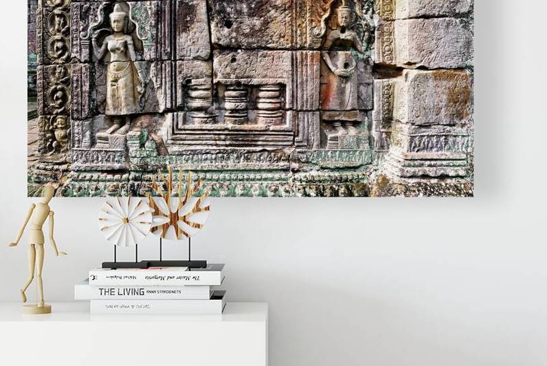 Ancient Cambodian temple wall with weathered stone carvings of f by Marco Brivio