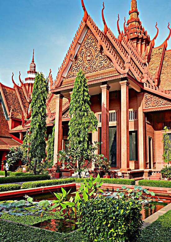 Ornate red Cambodian temple with lush gardens and lily pond. by Marco Brivio