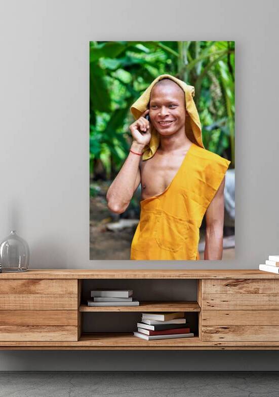 Smiling monk talks on phone with towel on head. by Marco Brivio