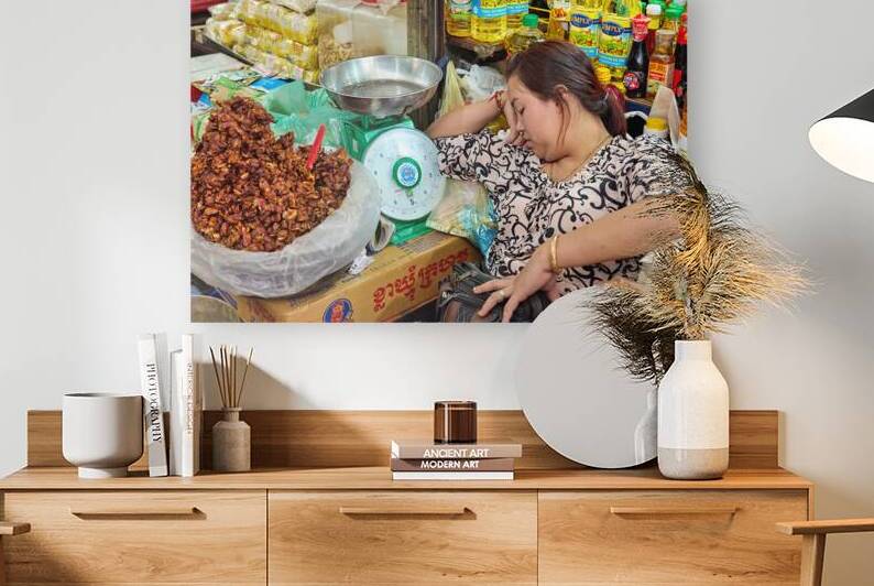 Woman sleeping at market stall amidst food and oils. by Marco Brivio