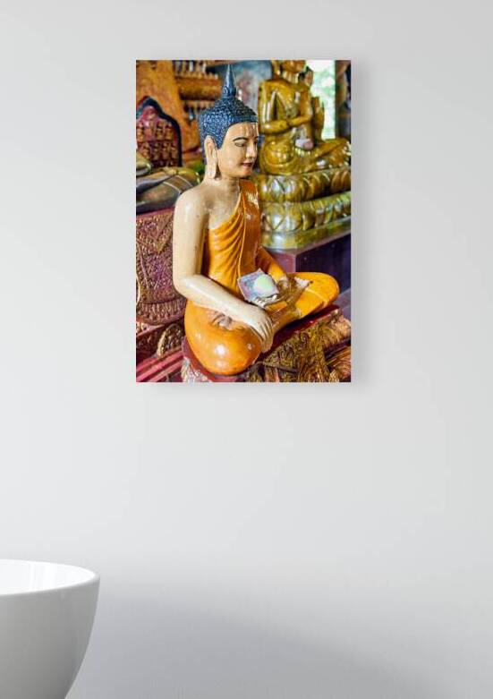 Seated Buddha statue with money and lotus offering. by Marco Brivio