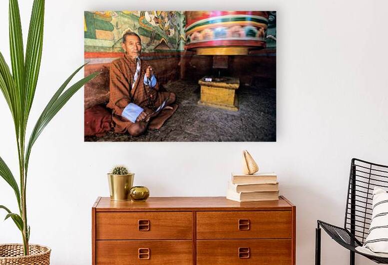 Bhutanese man with prayer beads and spinning prayer wheel. by Marco Brivio