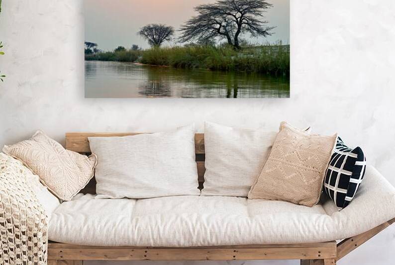 Banks of Okavango River at dusk in Namibia with setting sun by Marco Brivio