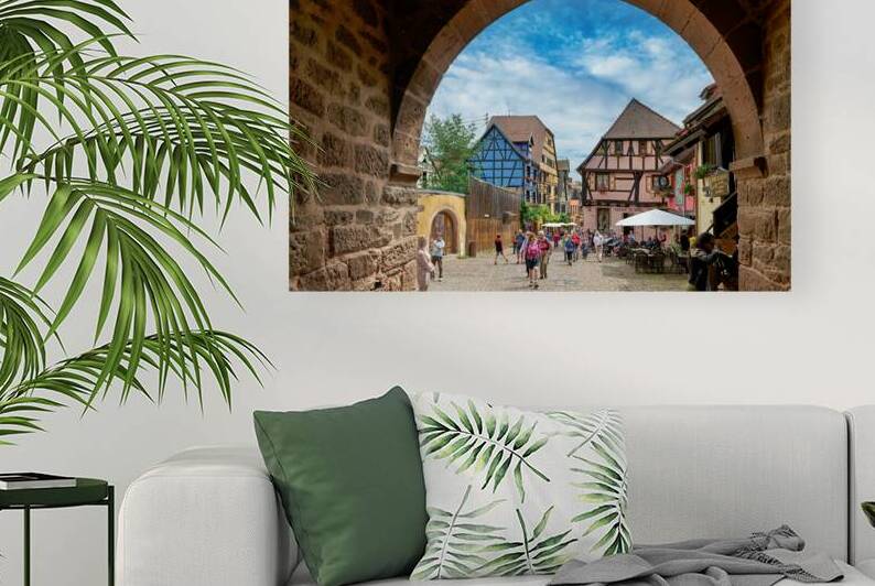 Visitors explore Riquewihr with timber framed houses under blue  by Marco Brivio