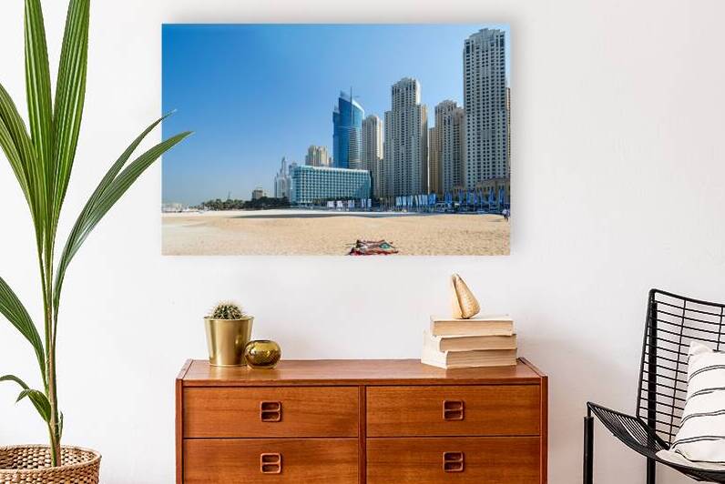 Sunbathers enjoy beach near city skyline in Dubai UAE by Marco Brivio