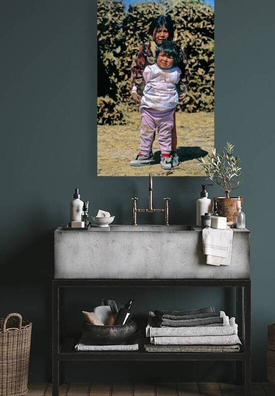 Two indigenous children one holding another outdoors. by Marco Brivio