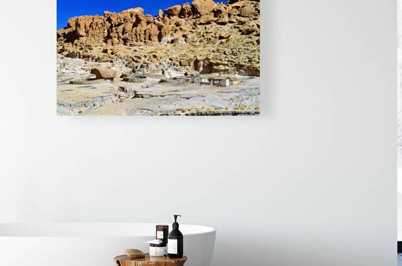 Rocky desert landscape with blue sky and small stone buildings. by Marco Brivio