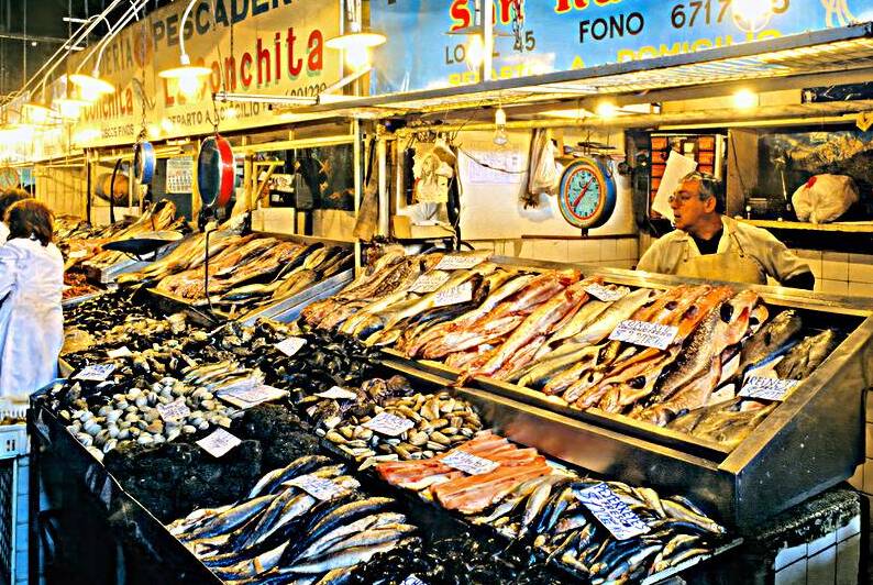 Bustling fish market with fresh seafood and vendors. by Marco Brivio