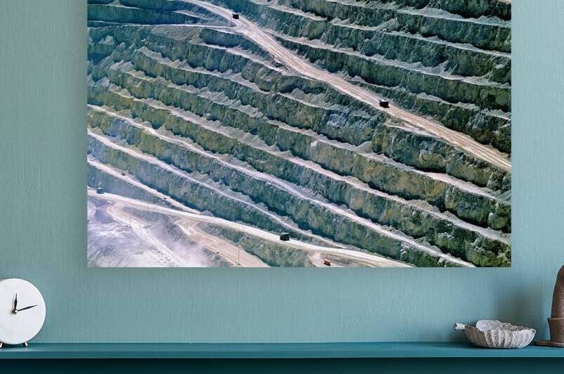 Large open pit mine showing terraced levels and mining trucks. by Marco Brivio